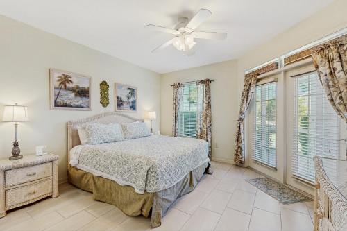 una camera da letto con un letto e un ventilatore a soffitto di Coastal condo with pool, lanai, washer/dryer, & elevator a Saint Augustine Beach