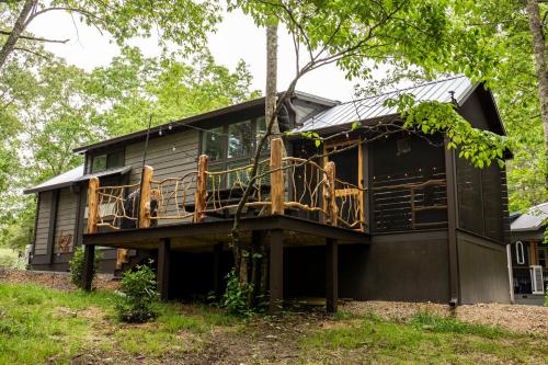 a black house with a wrap around deck at Creekside Gem, Hot Tub, Sleeping Porch, Fire Pit in Mentone