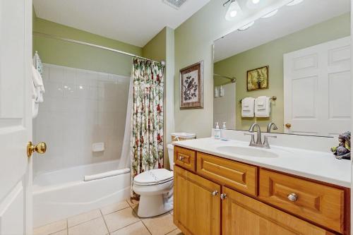 un bagno con lavandino, WC e doccia di Coastal condo with pool, lanai, washer/dryer, & elevator a Saint Augustine Beach