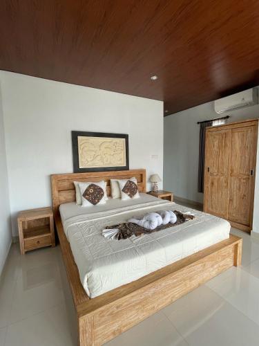 a bedroom with a large bed with a wooden headboard at Suntari Homestay in Ubud