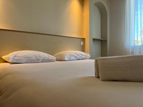 a bed with two pillows on it in a room at Adonis Sanary Grand Hôtel des Bains in Sanary-sur-Mer