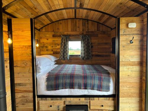 a bedroom in a log cabin with a bed at Shepherd's Huts at Cotswold Hills Country Park in Chipping Norton