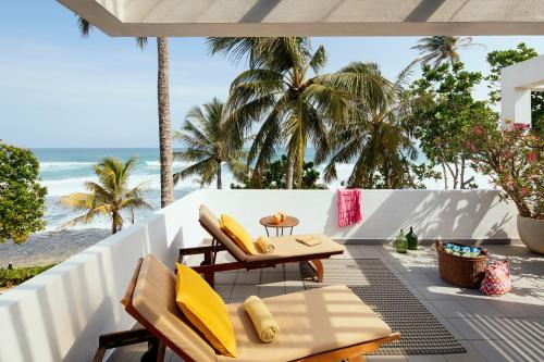 a balcony with chairs and a table and the beach at Owl and the Pussycat Hotel & Restaurant in Unawatuna