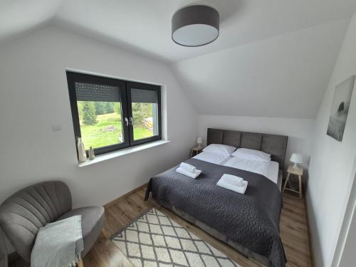 a bedroom with a bed and a chair and a window at Domek na szlaku in Szklarska Poręba