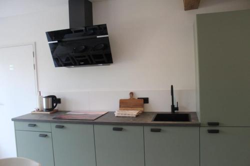 a kitchen with white cabinets and a stove top oven at Vakantie boerderij Pepinushof - 't Hofje in Maria-Hoop