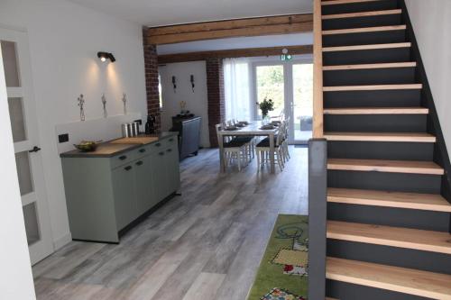 a kitchen and dining room with a staircase in a house at Vakantie boerderij Pepinushof - 't Hofje in Maria-Hoop