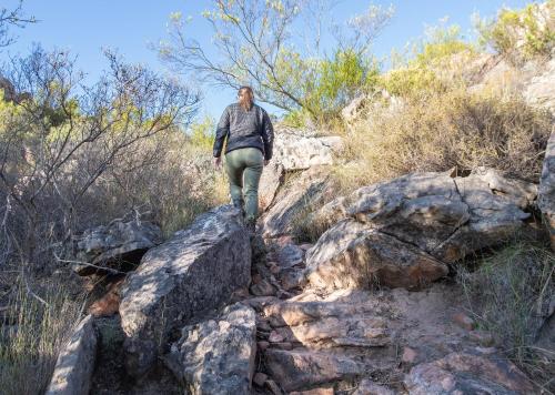 a man walking on rocks on a trail at Piekenierskloof Mountain Resort by Dream Resorts in Citrusdal