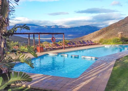 a swimming pool with chairs and mountains in the background at Piekenierskloof Mountain Resort by Dream Resorts in Citrusdal