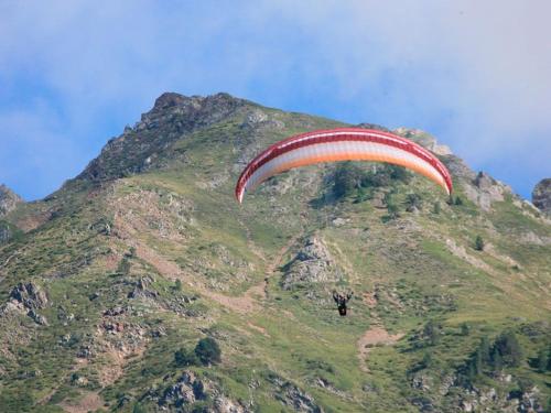a person riding a parachute over a mountain at La Maison Garrap dans le val d'Azun in Arrens-Marsous
