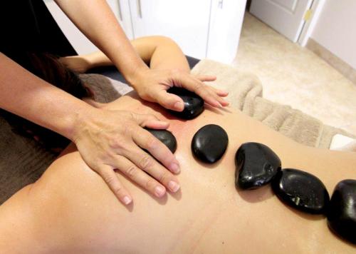 a woman getting a massage on her back with rocks at Piekenierskloof Mountain Resort by Dream Resorts in Citrusdal