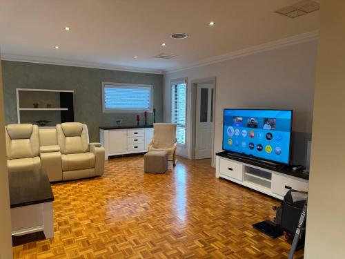 a living room with a flat screen tv and chairs at Geelong Chang House in Bell Post Hill