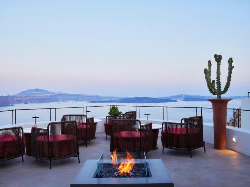 a patio with a table and chairs and a fire pit at Andronis Luxury Suites in Oia