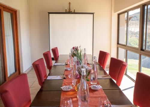 a dining room with a long table and red chairs at Piekenierskloof Mountain Resort by Dream Resorts in Citrusdal