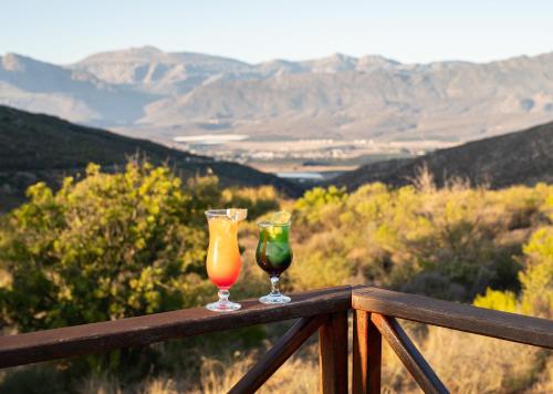 two wine glasses sitting on top of a wooden rail at Piekenierskloof Mountain Resort by Dream Resorts in Citrusdal