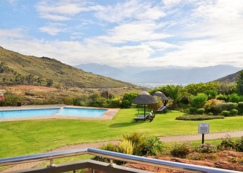 a garden with a swimming pool and mountains in the background at Piekenierskloof Mountain Resort by Dream Resorts in Citrusdal