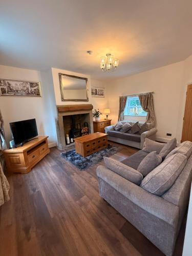 a living room with a couch and a tv at Wallnook Cottage Lindley Gem in Lindley