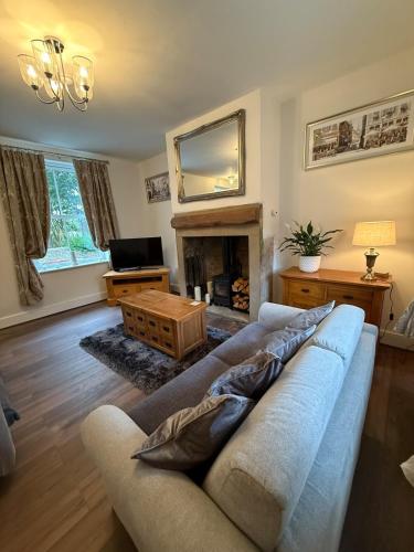 a living room with a couch and a fireplace at Wallnook Cottage Luxury Yorkshire Escape in Lindley