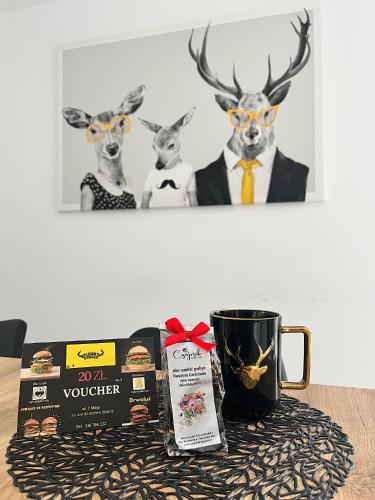 a table with a cup of coffee and some deer heads at Apartment Roku 2024 - JELEŃ & NATURA in Kudowa-Zdrój