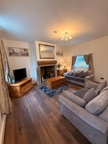 a living room with a couch and a tv at Wallnook Cottage Lindley Gem in Lindley