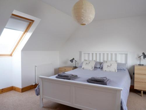 Un dormitorio con una cama blanca con toallas. en 1 Bed in Kinlochbervie 86897, en Rhiconich