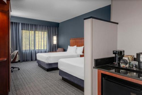 a hotel room with two beds and a television at Courtyard Pittsburgh Greensburg in Greensburg