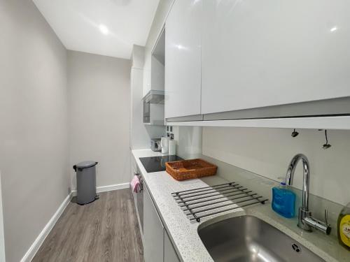 a kitchen with white cabinets and a sink at Clyde Inn in Milton Keynes