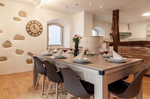 a large wooden table with chairs and a clock on the wall at Holiday&Stay Apartment Big Blue Beamer 10 Personen in Blaubeuren