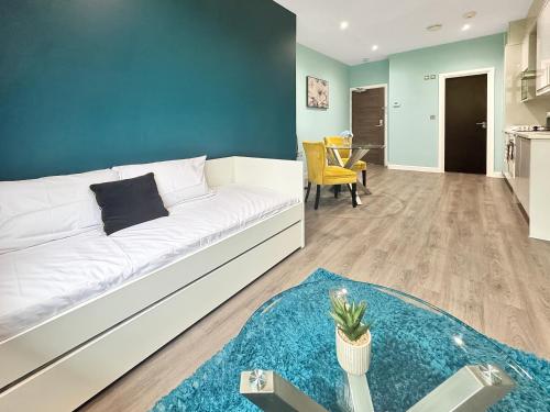 a living room with a white couch and a blue wall at Clyde Inn in Milton Keynes