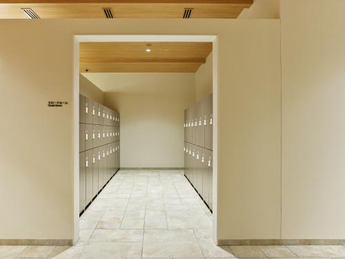 a walk in closet with white walls and wood ceilings at Mitsui Garden Hotel Kashiwa-no-ha Park Side - Chiba in Kashiwa