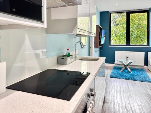 a kitchen with white counters and a blue wall at Clyde Inn in Milton Keynes