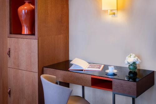 a desk in a room with a book and a vase at Hôtel La Bourdonnais by Inwood Hotels in Paris