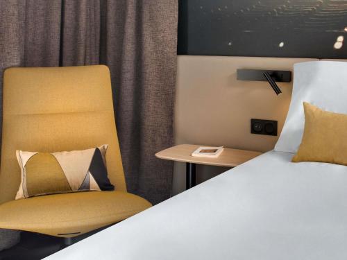 a bed and a chair in a room with a bed and a table at Mercure Montpellier Centre Comédie in Montpellier