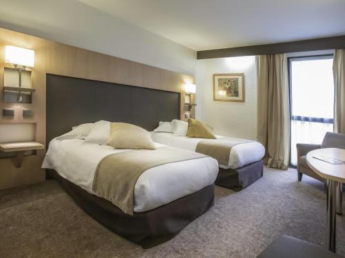 a hotel room with two beds and a window at Mercure Montpellier Centre Comédie in Montpellier