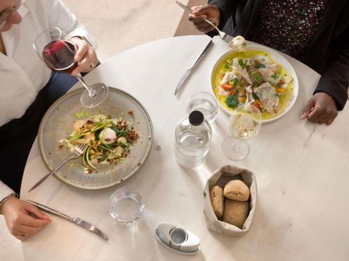 a group of people sitting at a table with plates of food at Mercure Montpellier Centre Comédie in Montpellier