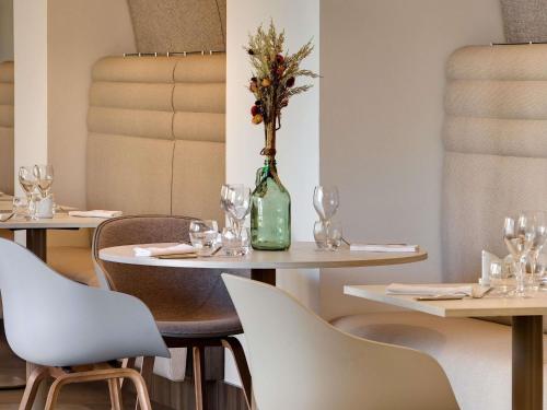 a dining room with tables and chairs and a vase with flowers at Mercure Montpellier Centre Comédie in Montpellier