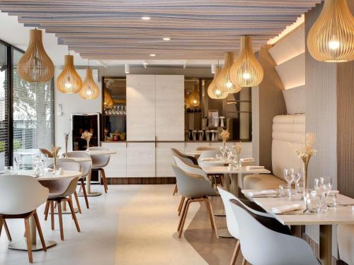 a restaurant with white tables and chairs and lights at Mercure Montpellier Centre Comédie in Montpellier