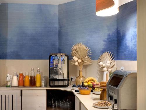 a kitchen with blue walls and a counter with a microwave at Mercure Montpellier Centre Comédie in Montpellier