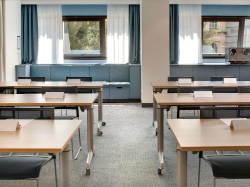an empty classroom with tables and chairs and windows at Mercure Montpellier Centre Comédie in Montpellier