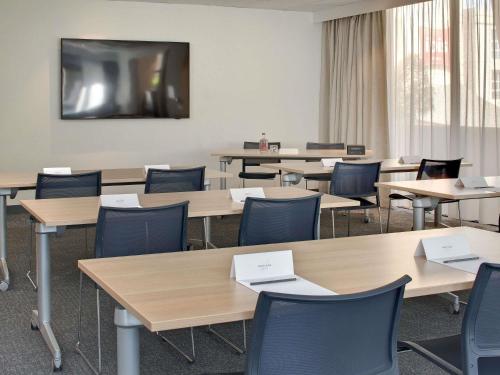 a classroom with tables and chairs and a flat screen tv at Mercure Montpellier Centre Comédie in Montpellier