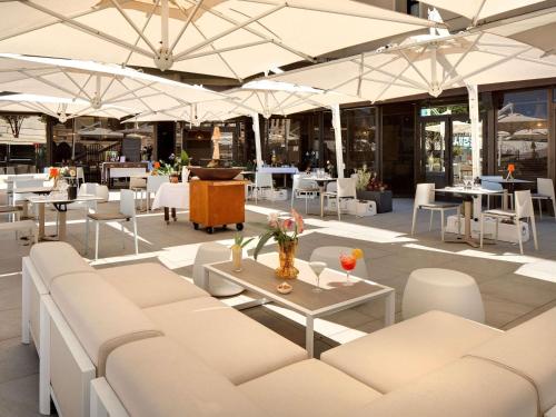a restaurant with white furniture and tables and chairs at Mercure Montpellier Centre Comédie in Montpellier