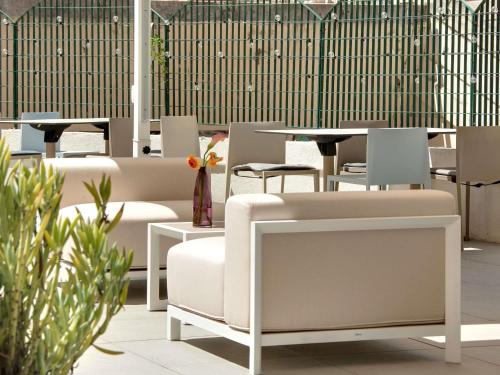 a restaurant with white chairs and tables and plants at Mercure Montpellier Centre Comédie in Montpellier