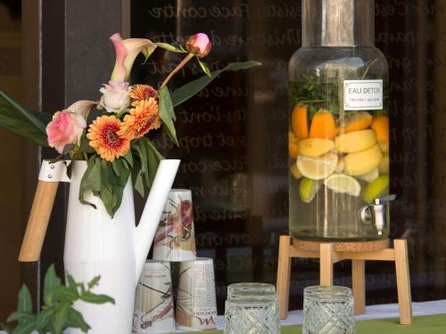 a white vase with flowers and a jar of fruit at Mercure Montpellier Centre Comédie in Montpellier