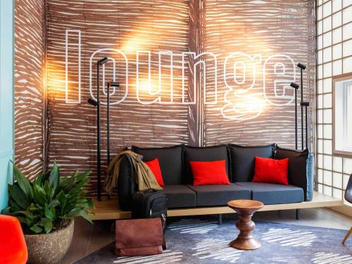 a living room with a blue couch with red pillows at ibis Amsterdam Centre Stopera in Amsterdam