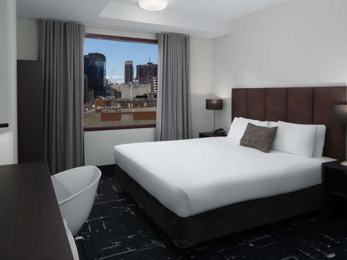 a hotel room with a bed and a view of a city at Mercure Welcome Melbourne in Melbourne