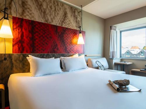 a hotel room with a large white bed with shoes on it at ibis Amsterdam Centre Stopera in Amsterdam