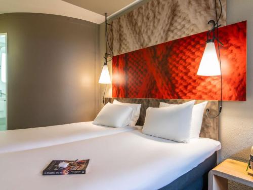 a bedroom with a bed with two pillows and a painting at ibis Amsterdam Centre Stopera in Amsterdam