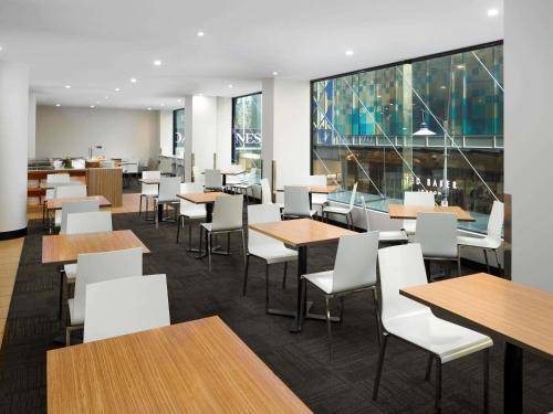 a dining room with tables and white chairs at Mercure Welcome Melbourne in Melbourne