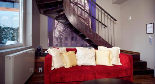 a red couch with pillows sitting under a staircase at Home Hotel Folketeateret in Oslo