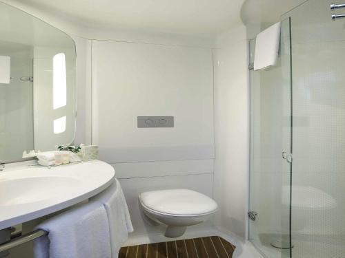a bathroom with a toilet and a sink and a shower at ibis Sydney Airport in Sydney