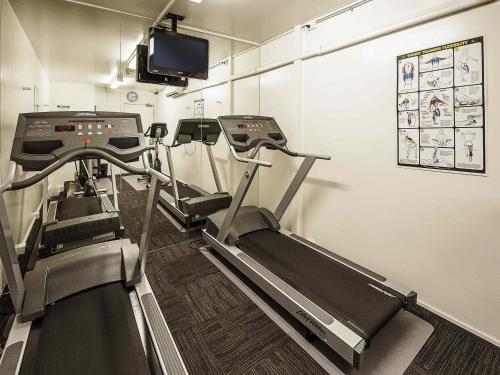a gym with treadmills and a flat screen tv at ibis Sydney Airport in Sydney